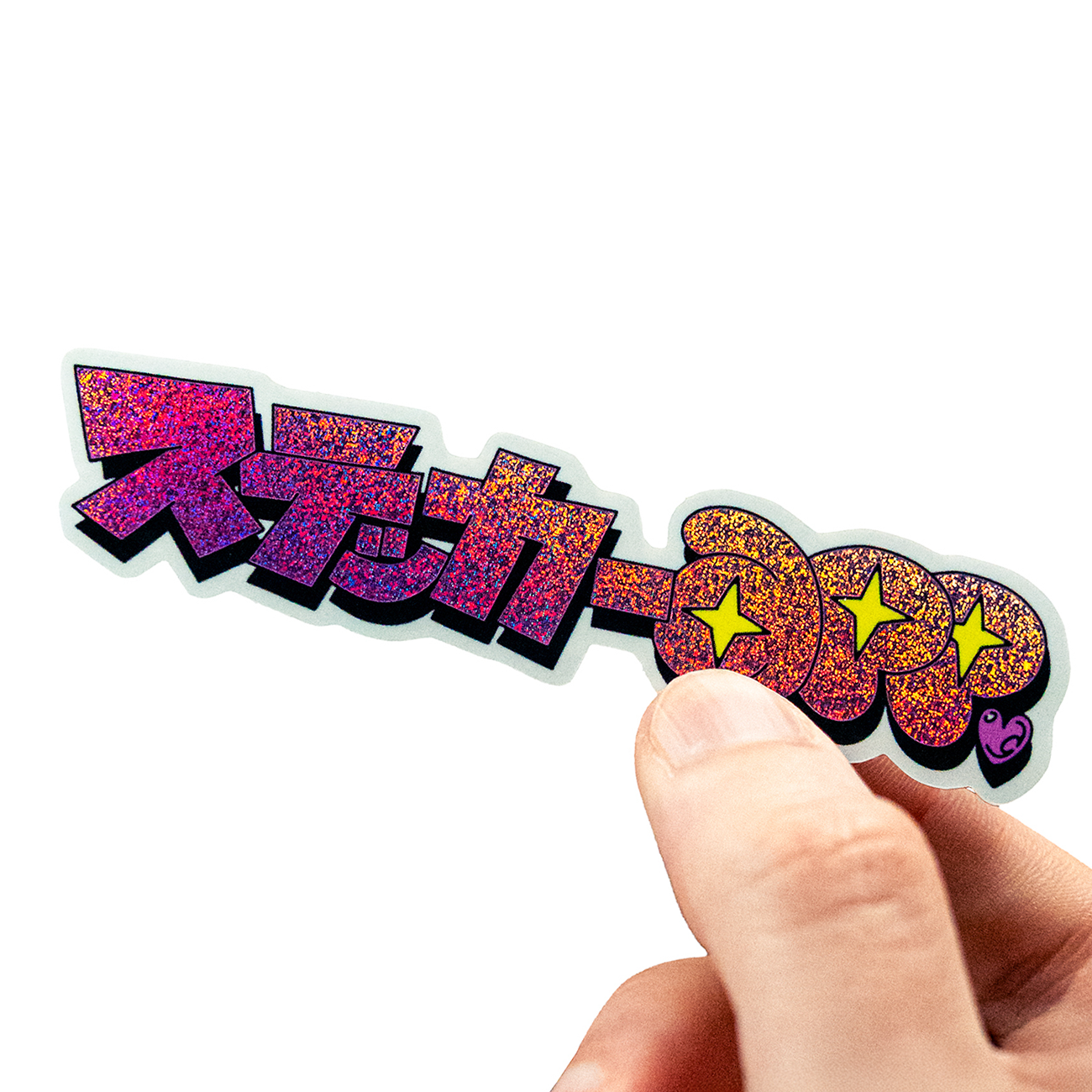 Hand holding a Pixie Dust sticker with Japanese text with full-color print, against a white background