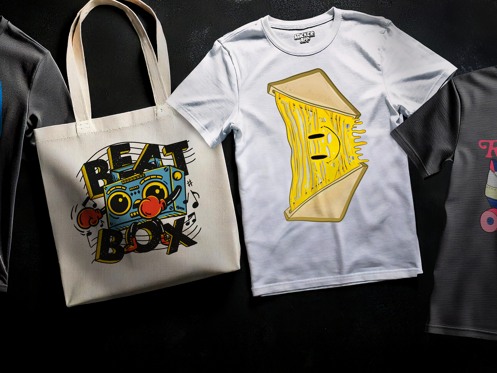 Heat transfer on a Tote bag with a colorful boombox design and a white t-shirt featuring a stylized sandwich graphic, displayed on a dark surface.
