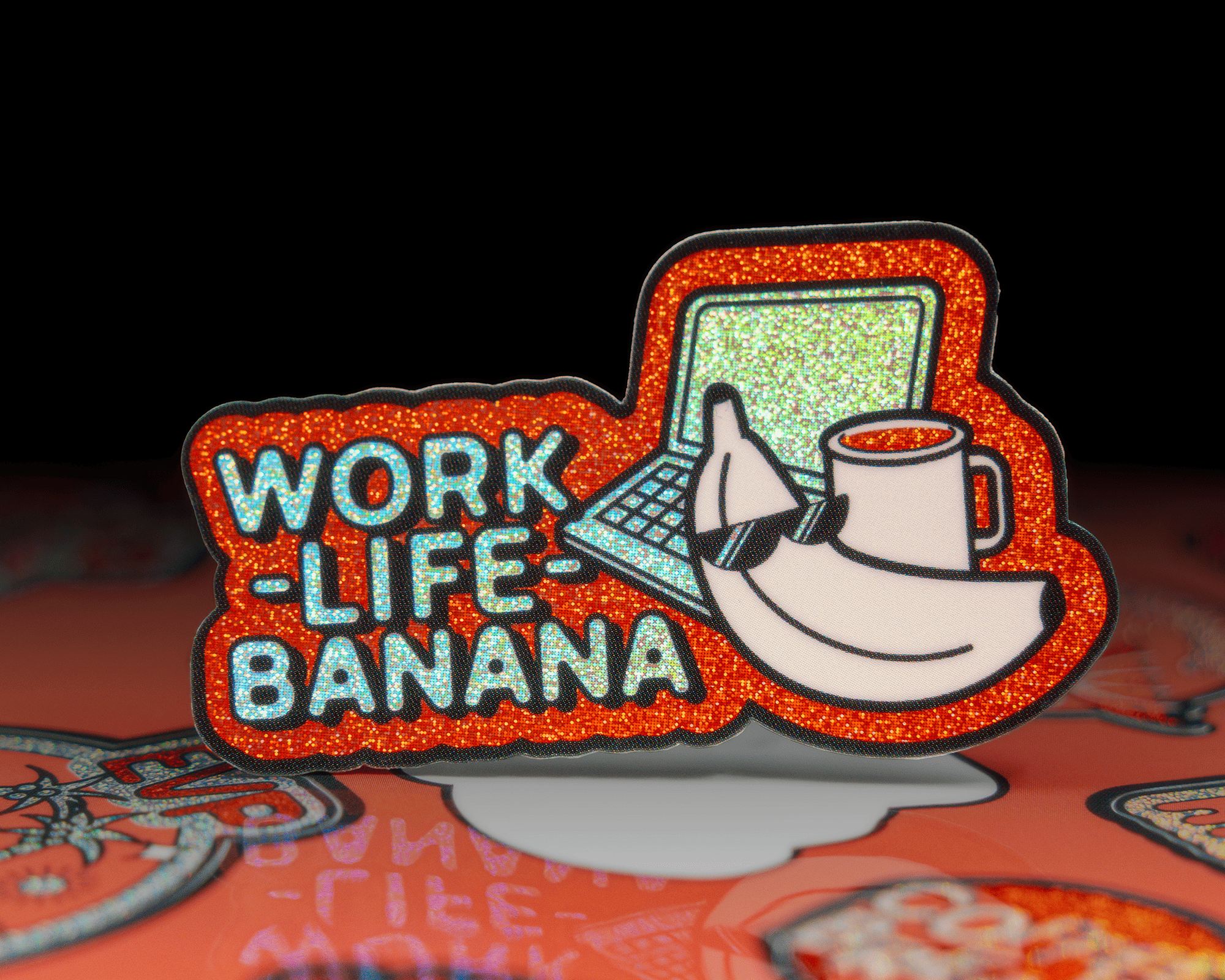 A glittery pixie dust sticker with "Work-Life-Banana" text, featuring a banana with sunglasses, a coffee mug, and a laptop.