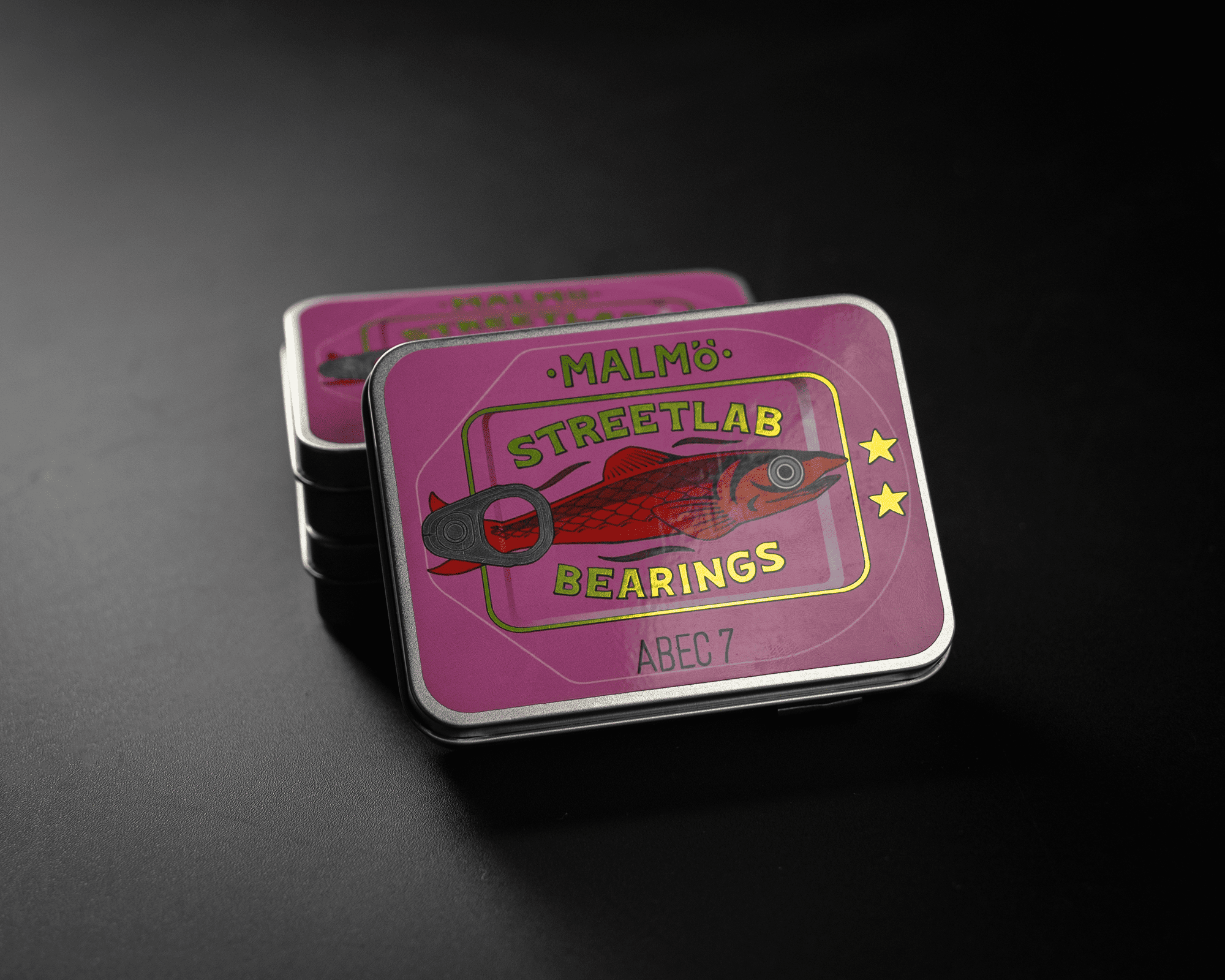 A metallic label. "Malmö Streetlab Bearings ABEC 7" with a fish graphic, set against a dark background.