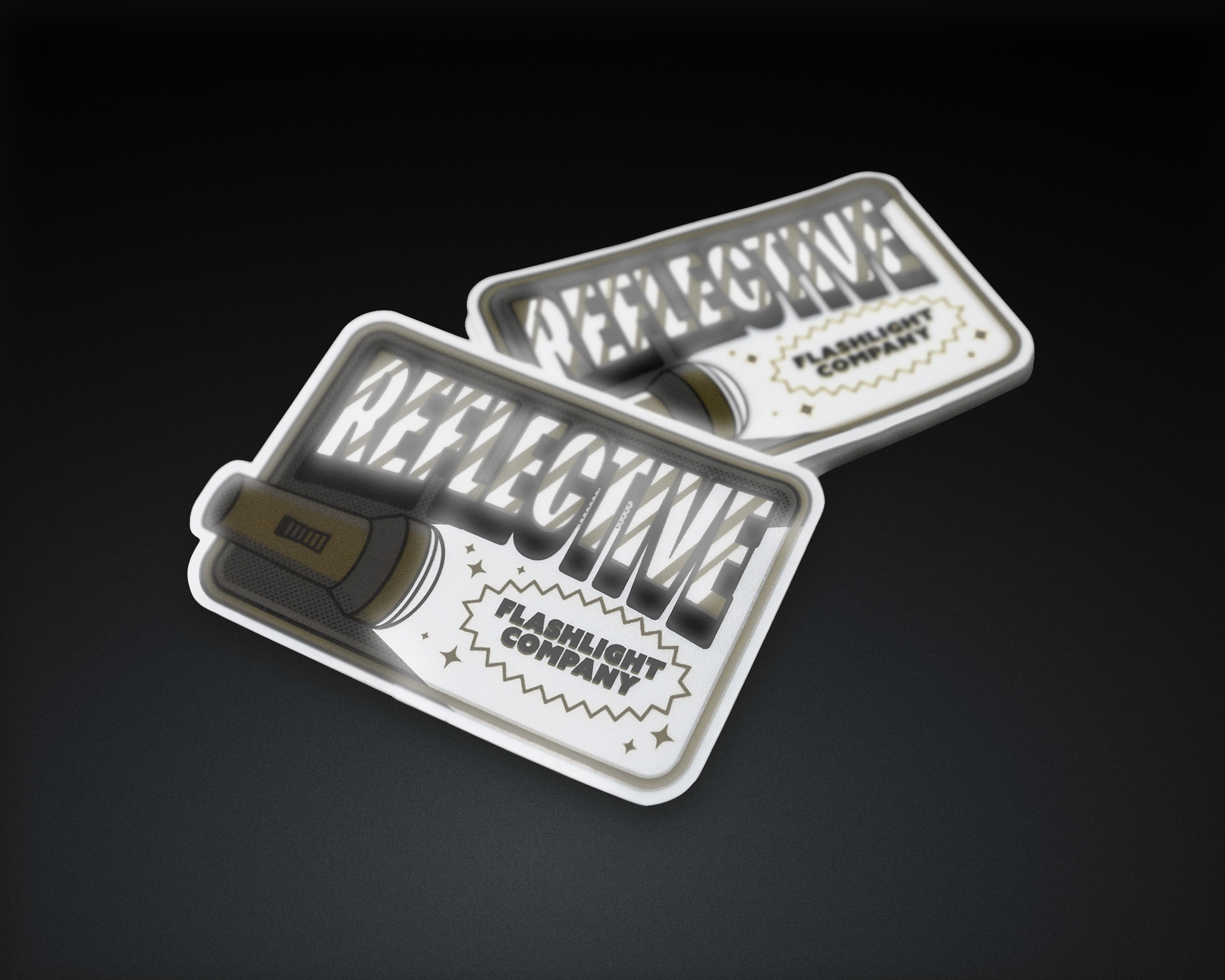 Two reflective stickers with a flashlight design and the text "Reflective Flashlight Company" on a dark surface.