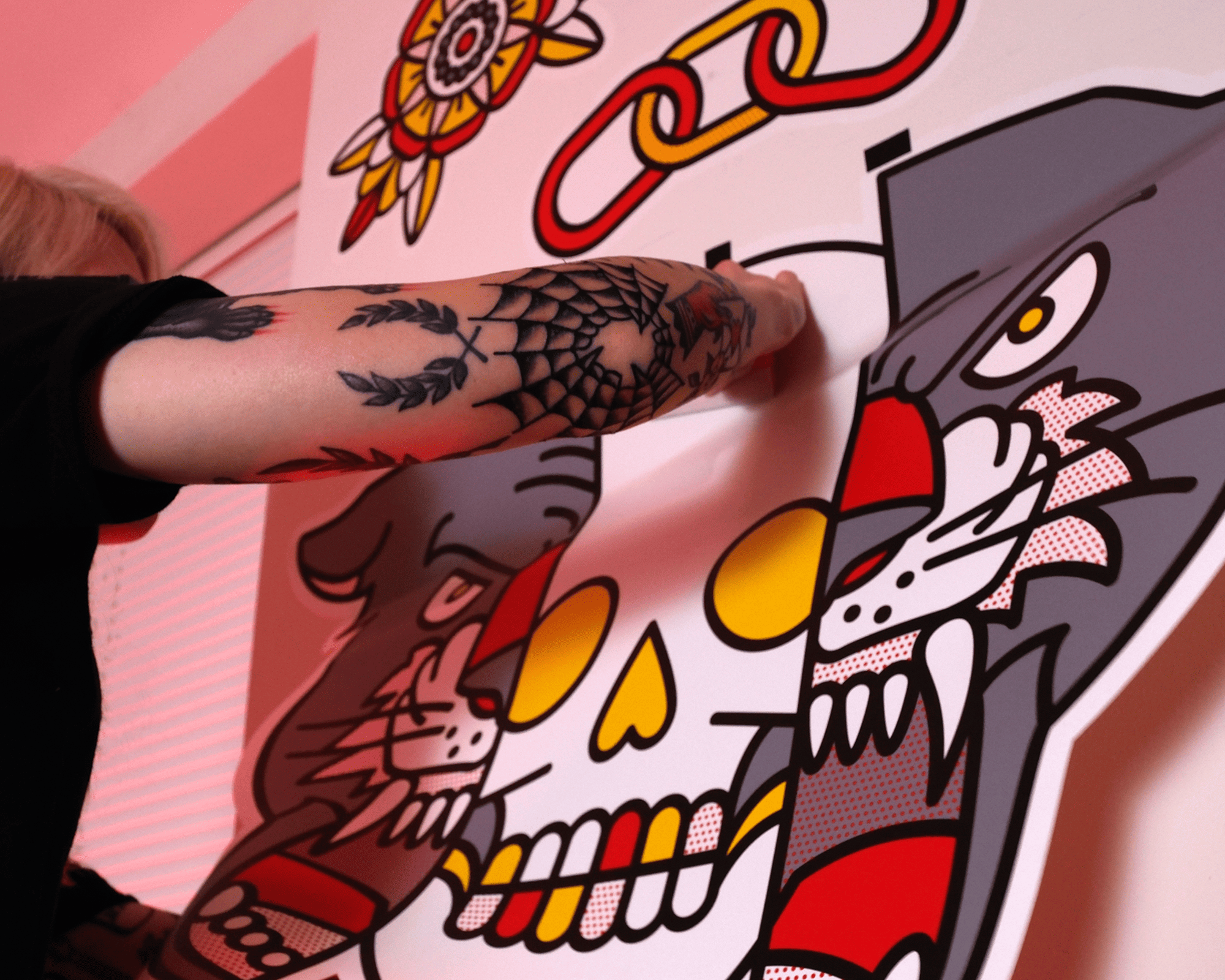 Person with tattoos applies vibrant, graphic wall stickers of a skull and animals on a wall.