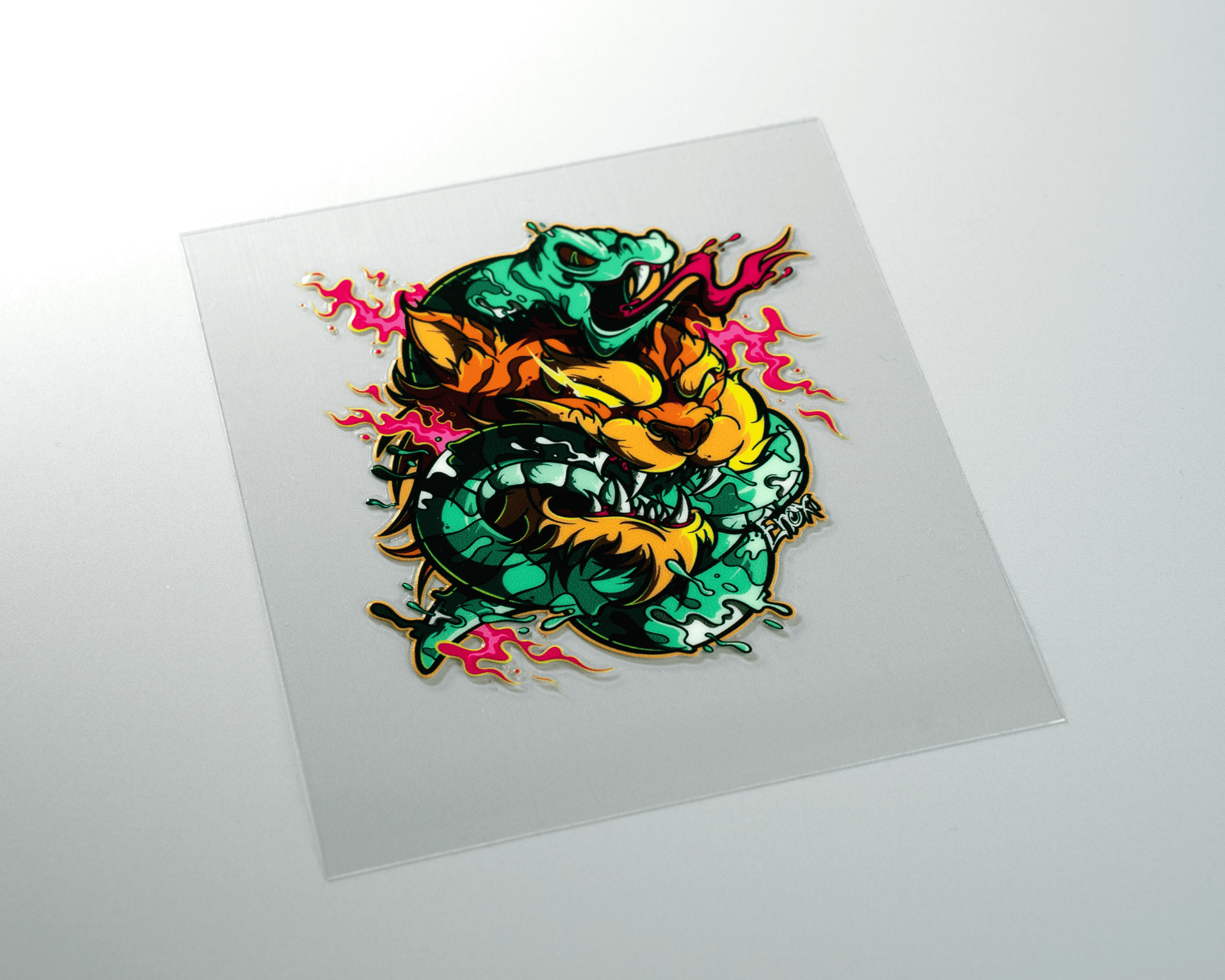 A colorful uv dtf sticker of a fierce, stylized dragon with vibrant green and orange hues, surrounded by pink flames on a clear background.