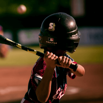 A young baseball player wearing a helmet with StickerApp logo.