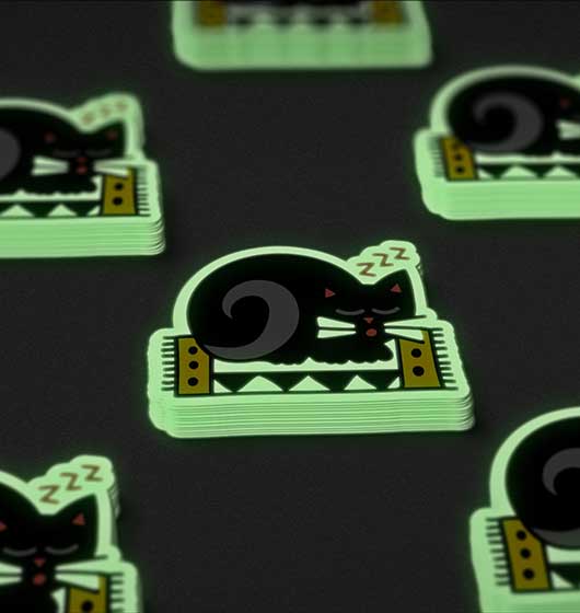 Ein Haufen im Dunkeln leuchtender Aufkleber einer Katze, die auf einem Tisch liegen