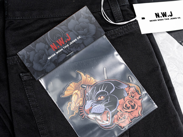 Freiform-Sticker mit Panther und Rosen in einem Sticker-Pack mit "N.W.J Never Wash This Jeans Co."-Headerkarte auf schwarzer Jeans