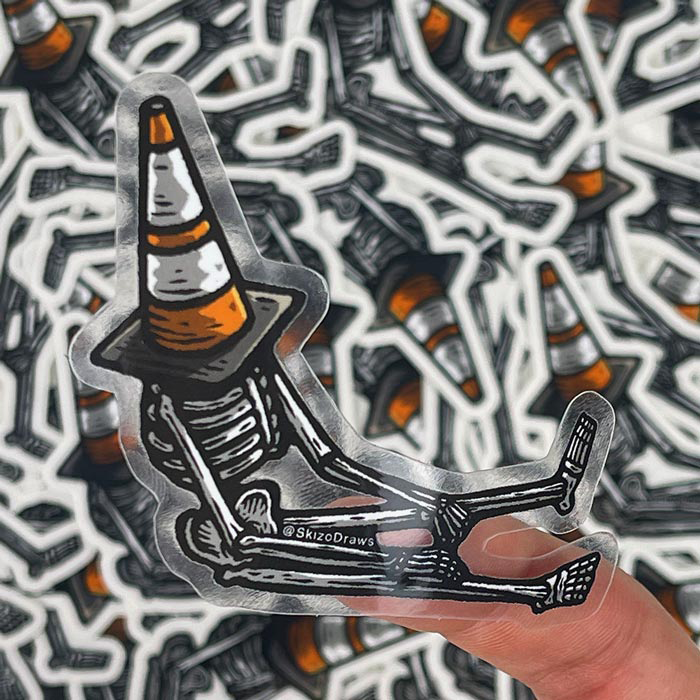Transparenter Freiform-Sticker mit einem Skelett, das mit einem Leitkegel auf dem Kopf auf dem Boden sitzt, vor einem Hintergrund aus Stickern.