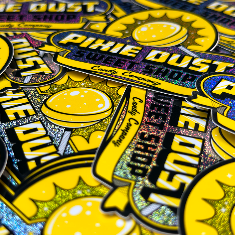 Ein Stapel gelber und schwarzer Pixie Dust-Aufkleber, die übereinander liegen